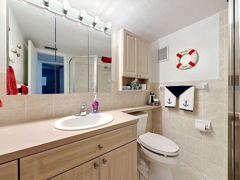 Nautical inspired guest bath with beige tile finishes, a glass-enclosed shower, and a charming coastal decor that adds personality and warmth.