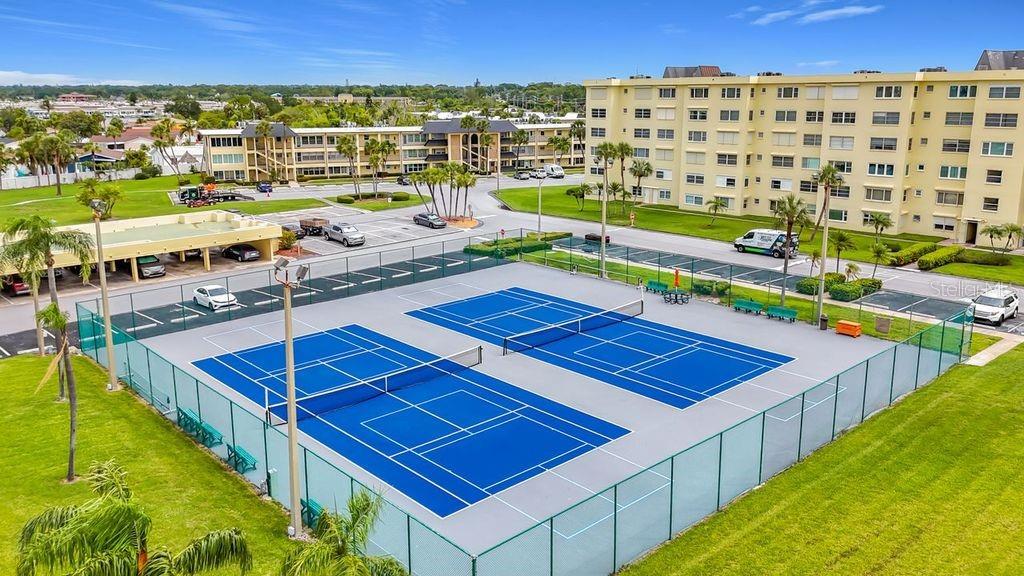 Resort-style community view featuring the Washington building, tennis and pickleball courts, and sparkling pool- all nestled around the tranquil bayou