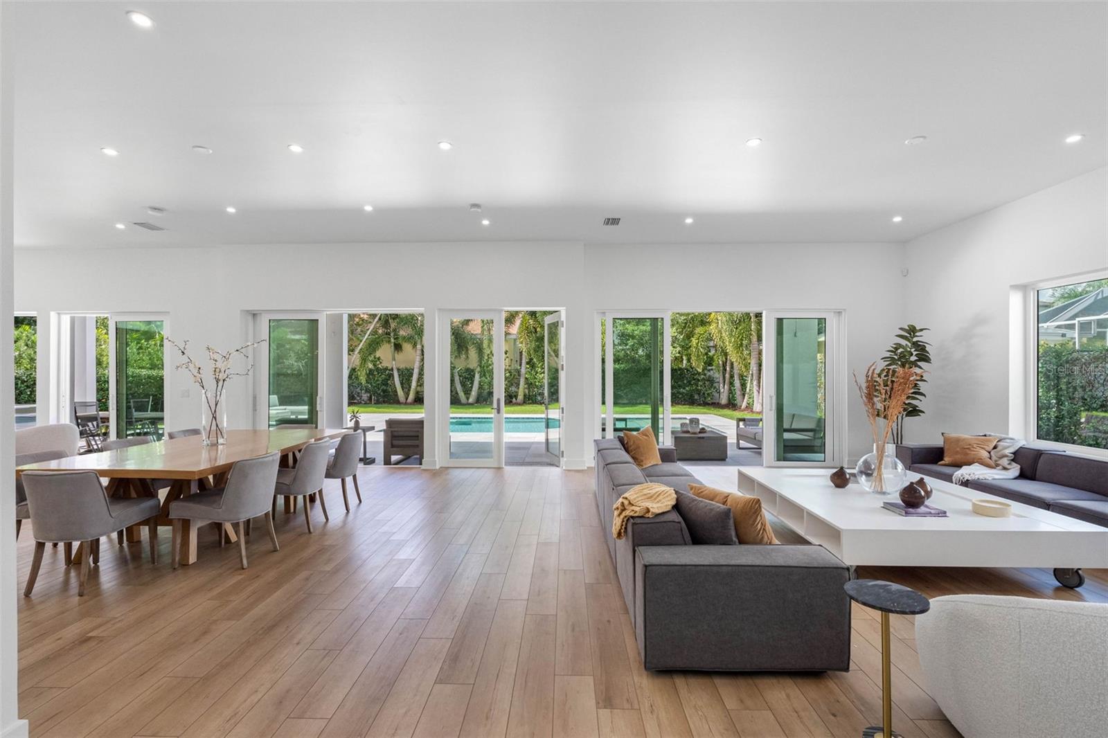 Multiple large sliding door open to your outdoor retreat paradise! The living room is on the right, the dining room in the middle and the kitchen on the left