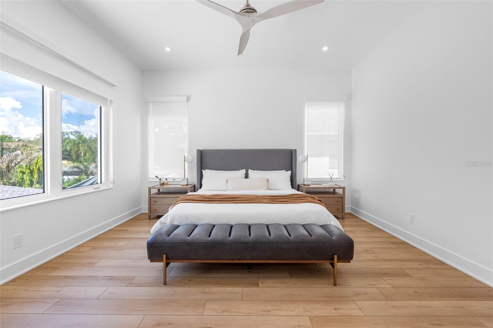French doors open to the ample master bedroom featuring his and her walk-in closet with built-ins, dimmable lights, window treatment and Minka ceiling fan, known for their quiet operation and distinctive style