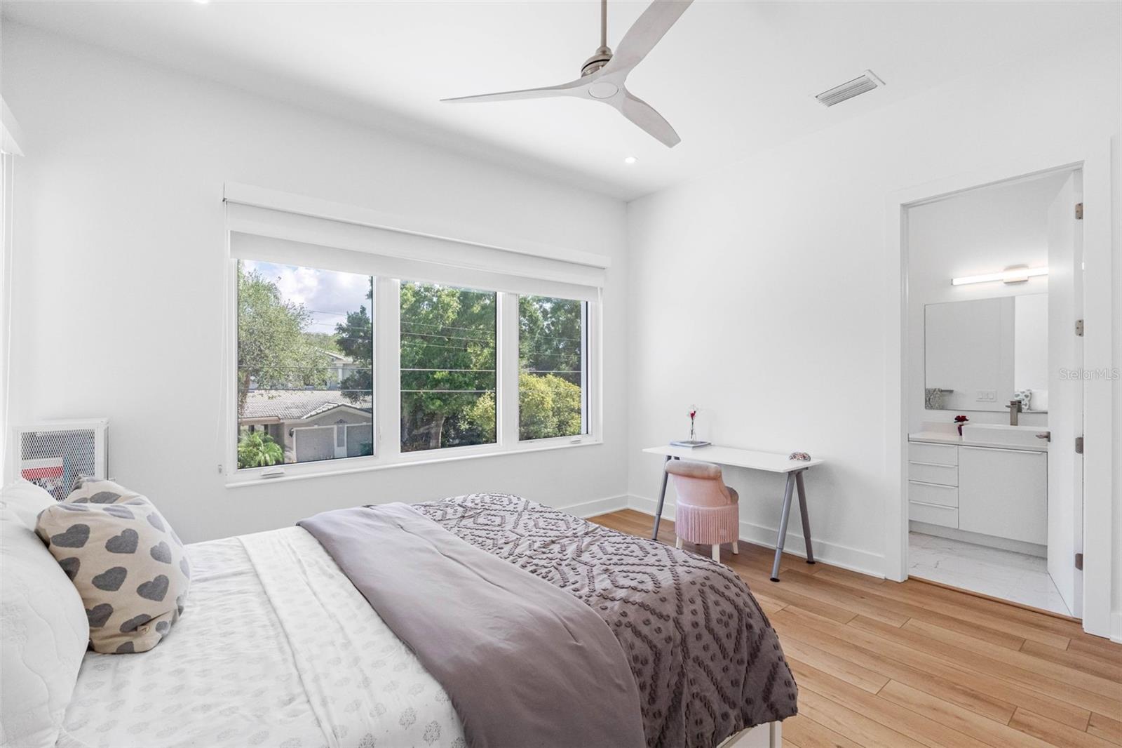 Bedroom 2 boasts en-suite bath with glass-enclosed shower, closet system, window treatment, dimmable lights, and Minka ceiling fan, known for their quiet operation and distinctive style