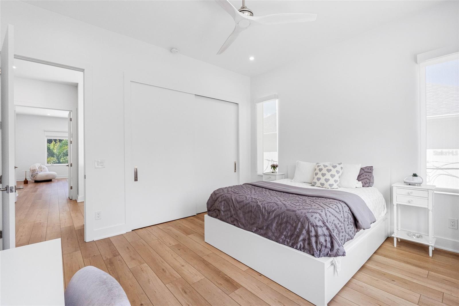 Bedroom 2 boasts en-suite bath with glass-enclosed shower, closet system, window treatment, dimmable lights, and Minka ceiling fan, known for their quiet operation and distinctive style