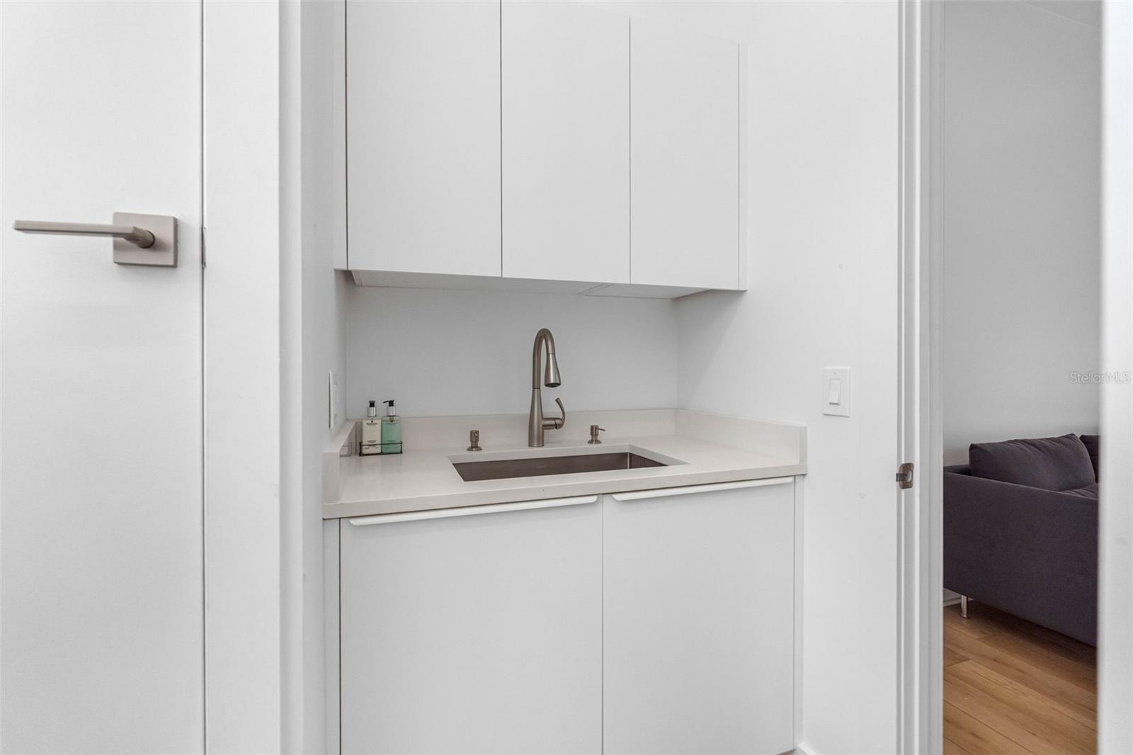 The laundry room boasts a sink, cabinetry, and a hanging rack for added convenience.