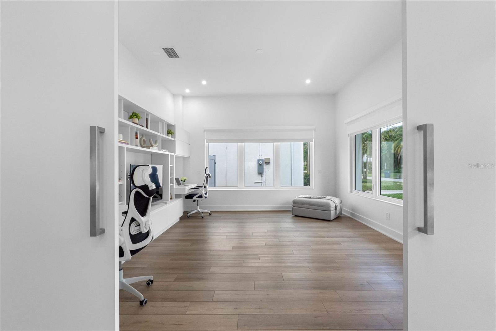 Barn doors open to a private office with built-ins, that can be used as a fifth bedroom, family room or flex room. In front of the office space, there is a full bath.