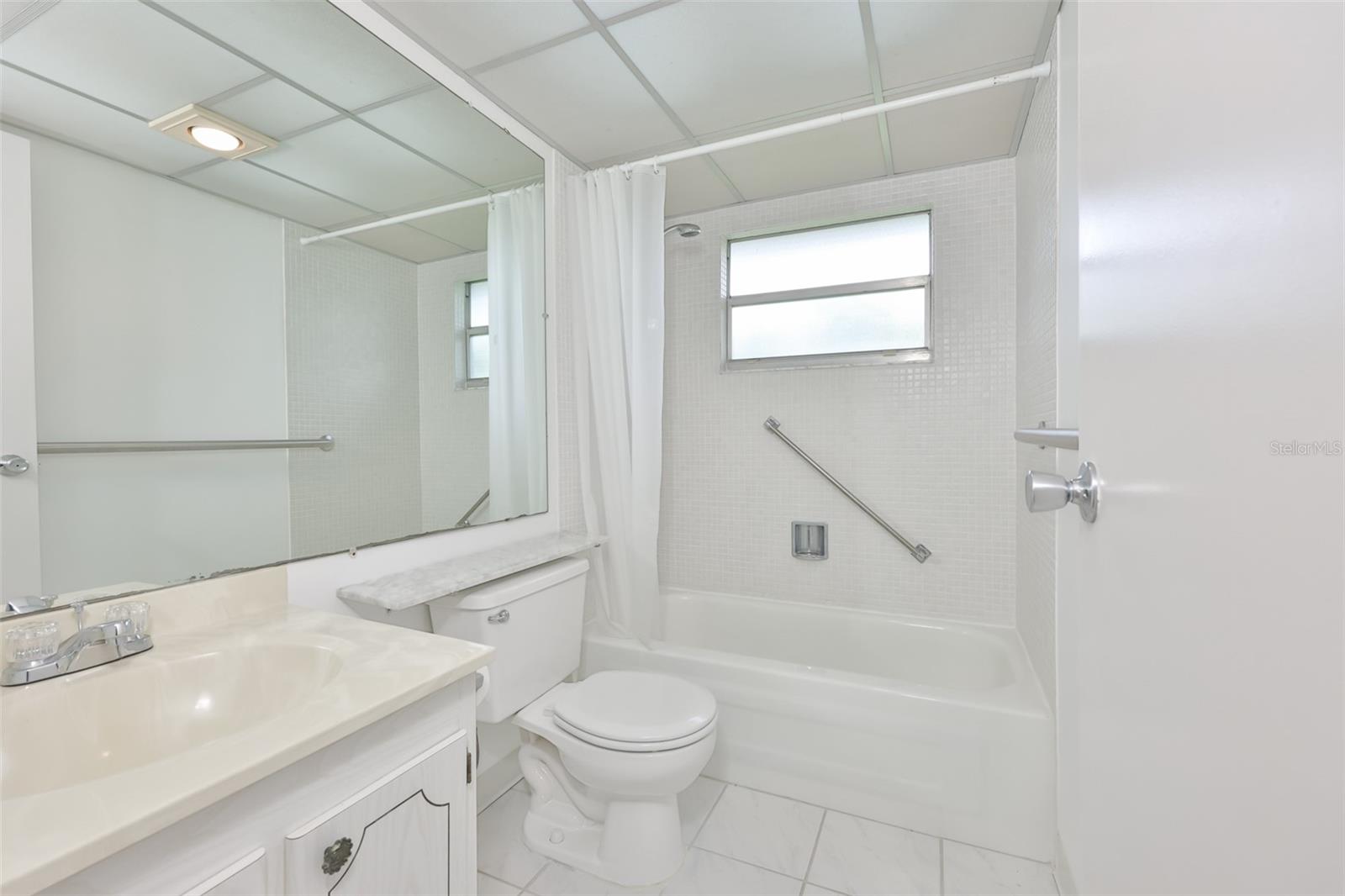 Bright, clean bathroom has had the shower updated and new grab bars added.