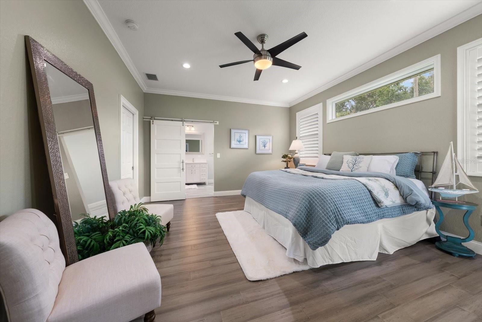 Primary bedroom suite offers natural light from transom windows and separate private access to pool area.