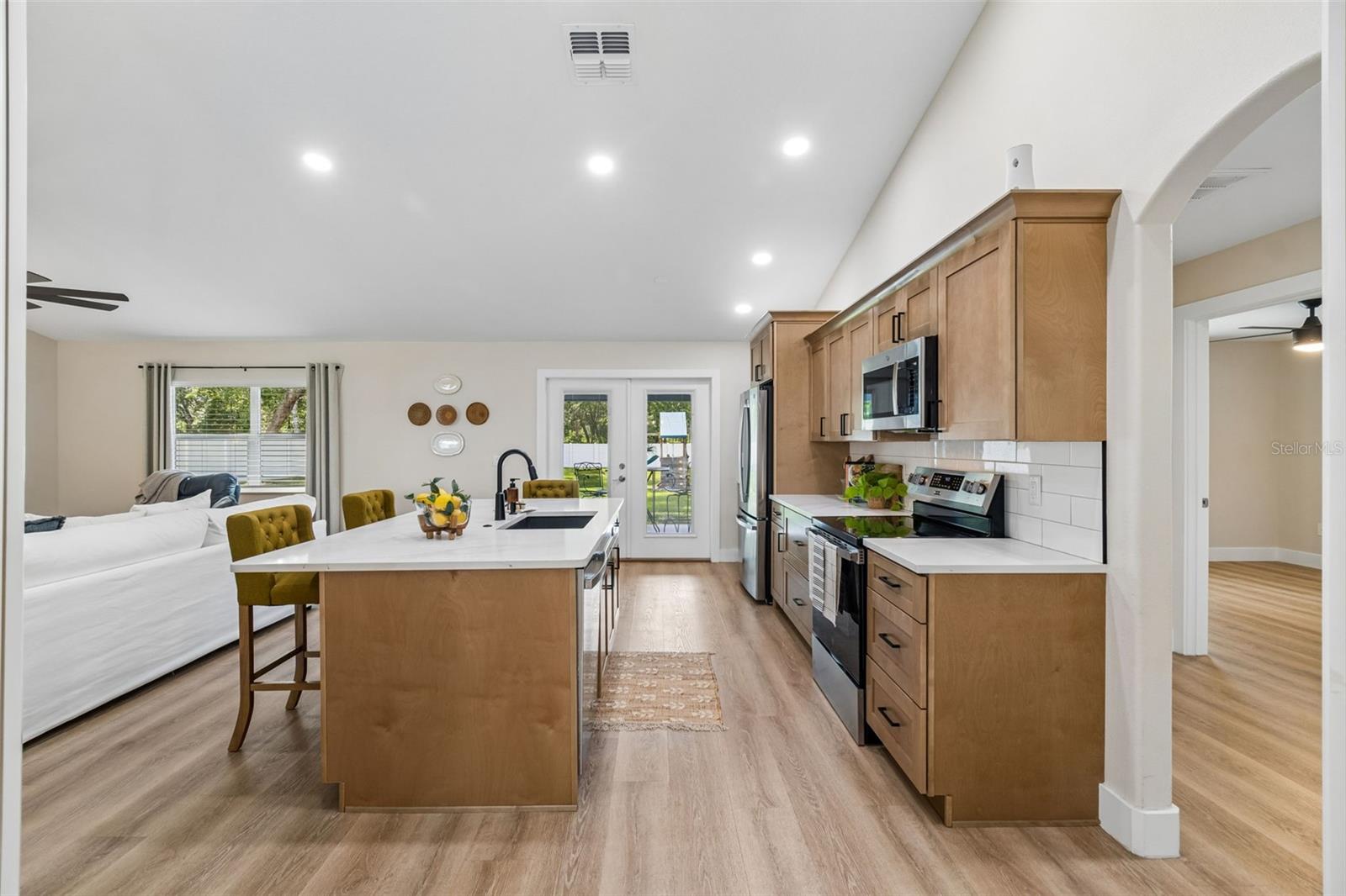 Chef's kitchen has all been remodeled with wooden cabinets and quartz countertops.  Archway to the right are bedrooms 2 and 3 and bathroom 2.