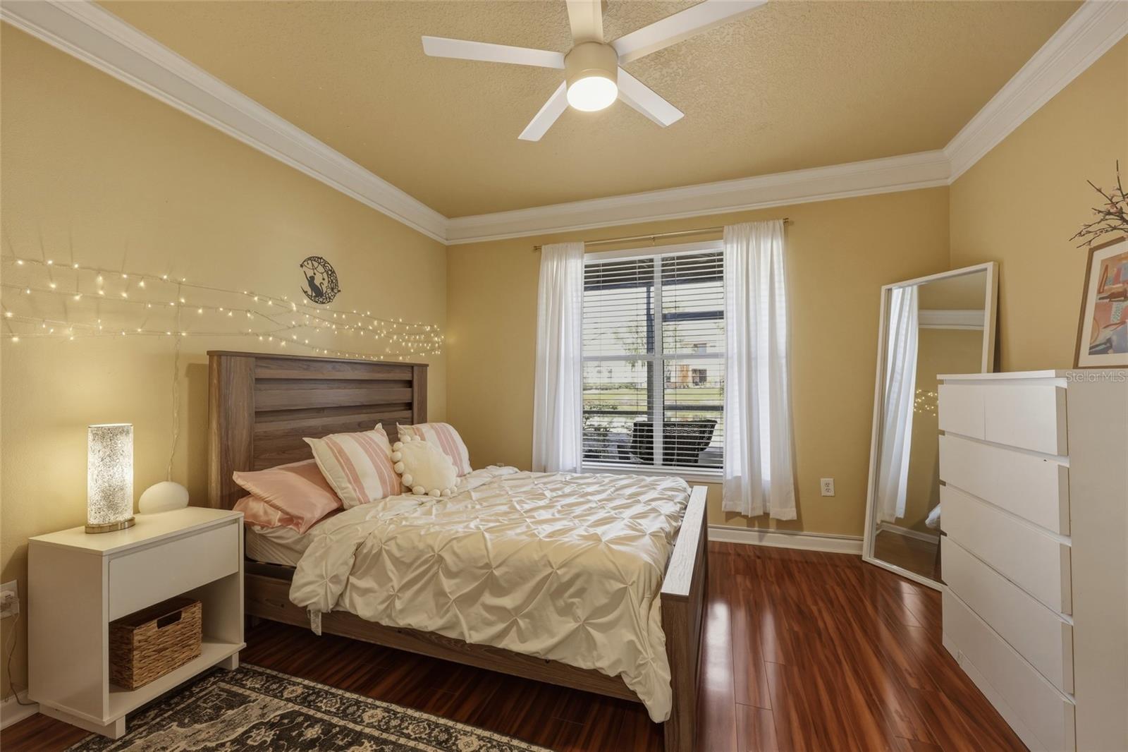 Crown molding flows into bedroom along with large window allowing natural lighting to shine in
