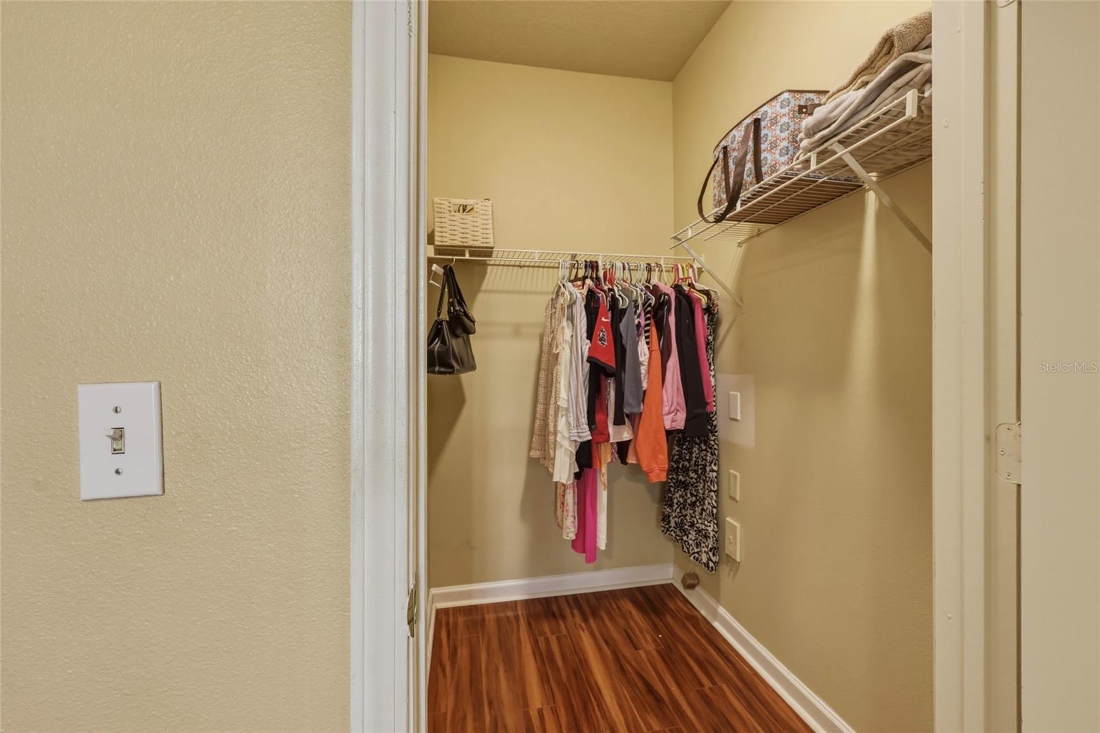 Spacious walk-in closet with laminate flooring in bedroom