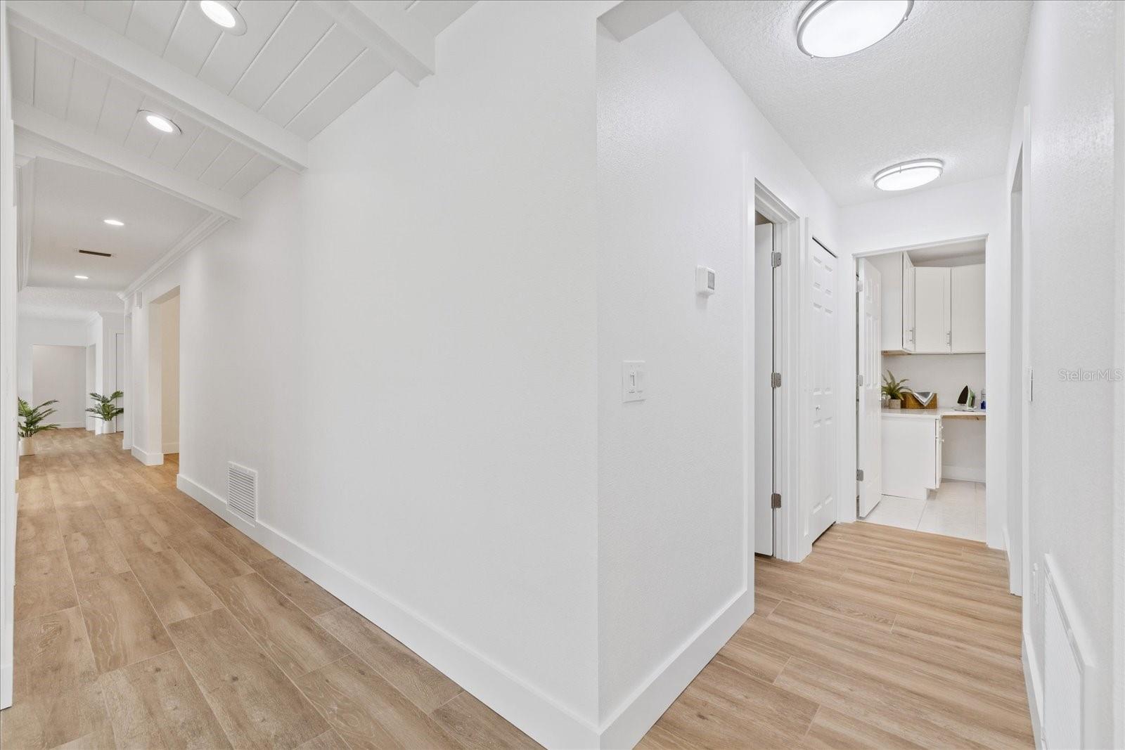 Looking from side entry to hallway towards kitchen and on right guest bathroom, bedroom and laundry room.