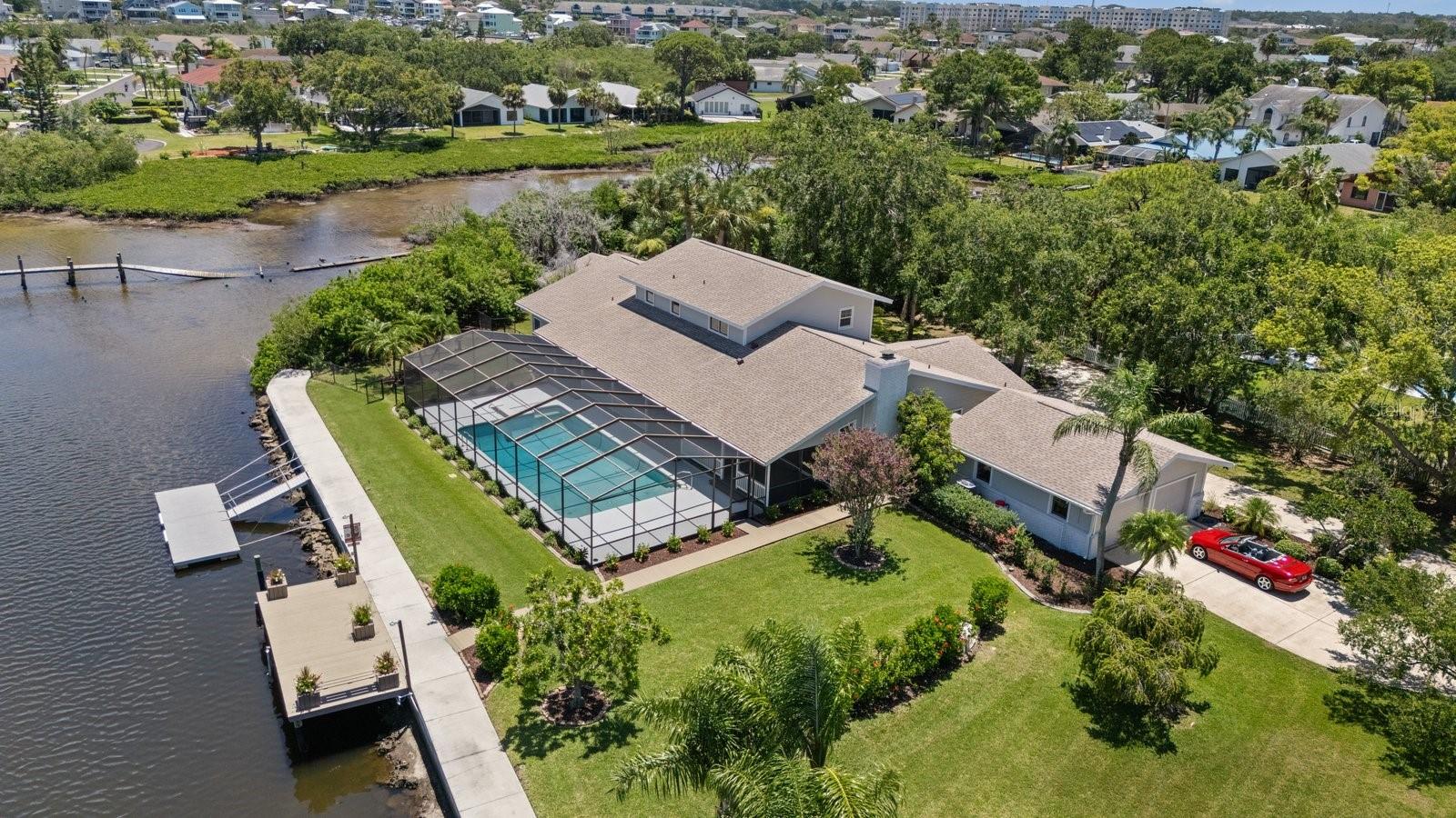 Aerial view of luxury home, pool, and docks with detached two car garage