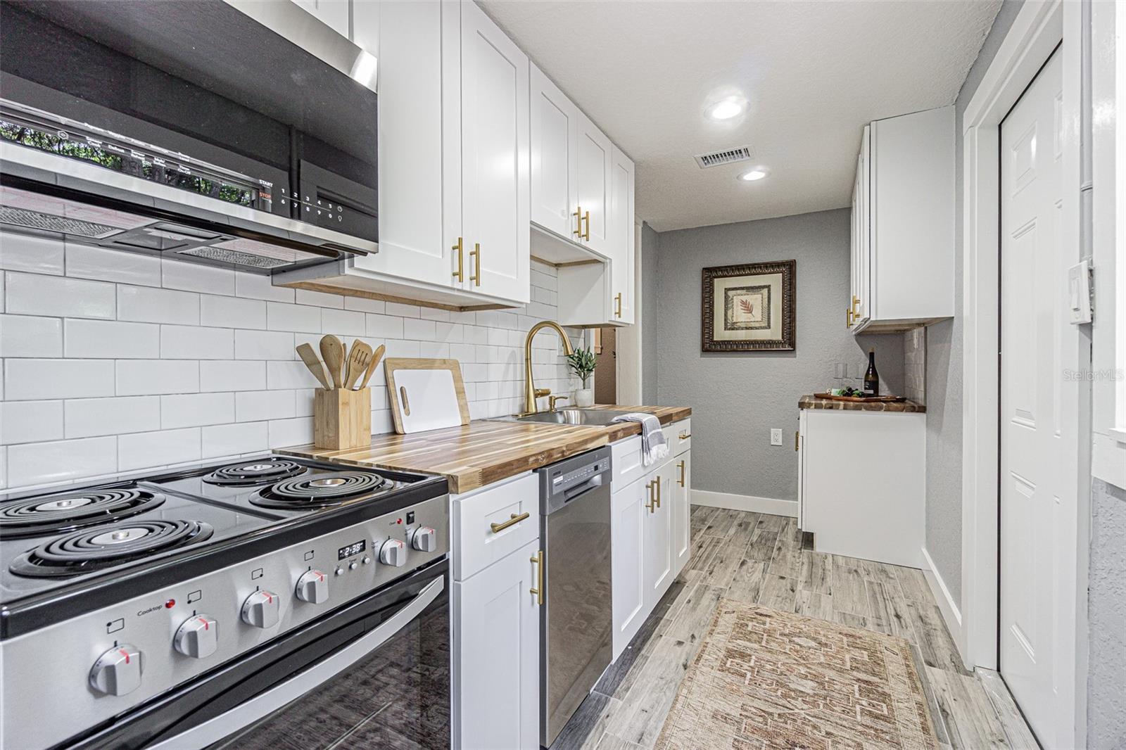 Love the mixture of earth tones added by the Butcher Block countertop set against the white shaker cabinets and got toned cabinet pulls...so elegant yet so efficient
