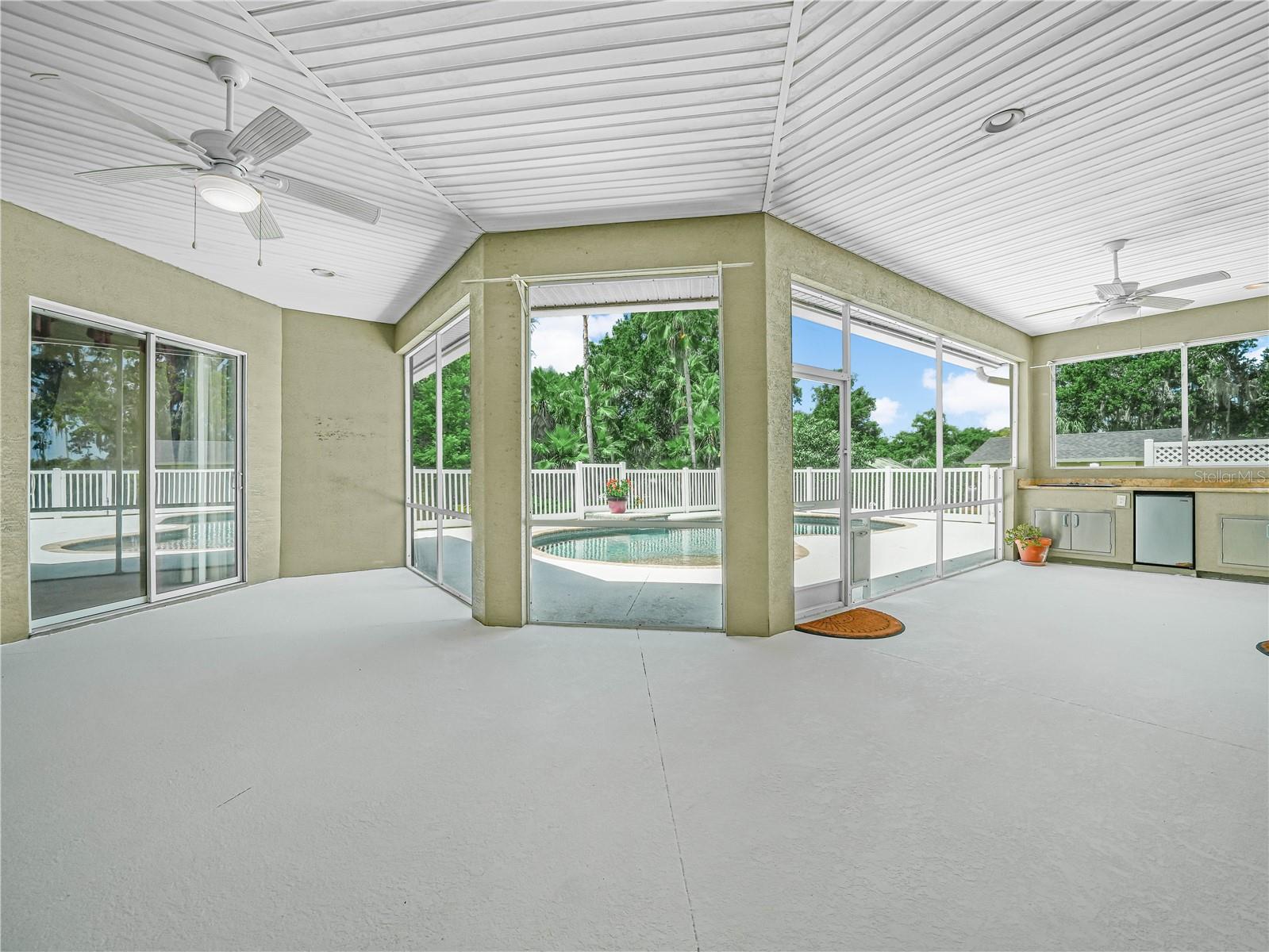 Expansive screened in patio complete with outdoor kitchen and ceiling fans.