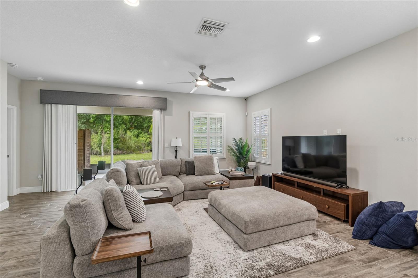 Light and bright family room with custom blinds on sliders and plantation shutters