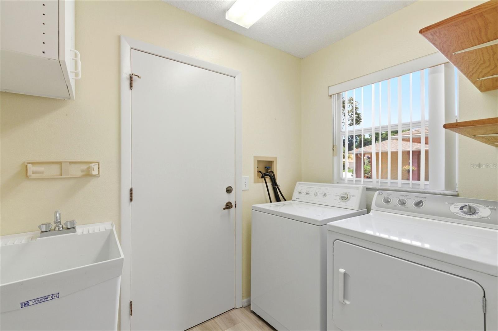 Inside laundry room with utility sink, leading to the garage