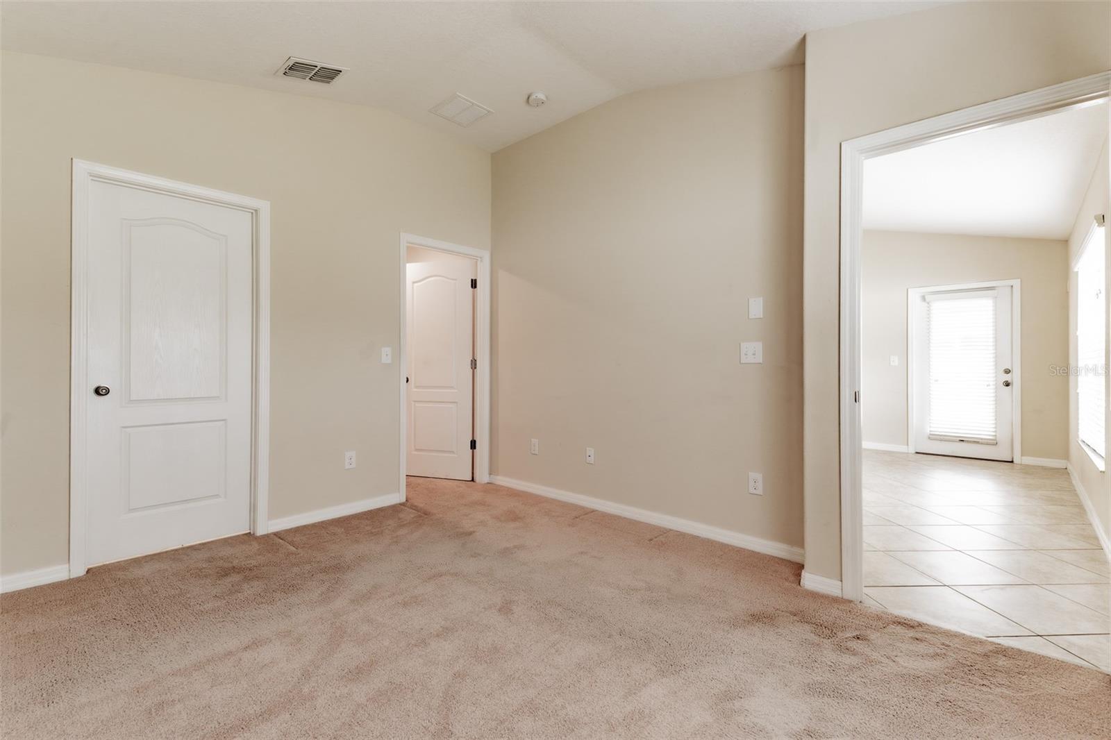 Primary bedroom looking to patio door. Bath on left and walk in closet to right of bathroom.