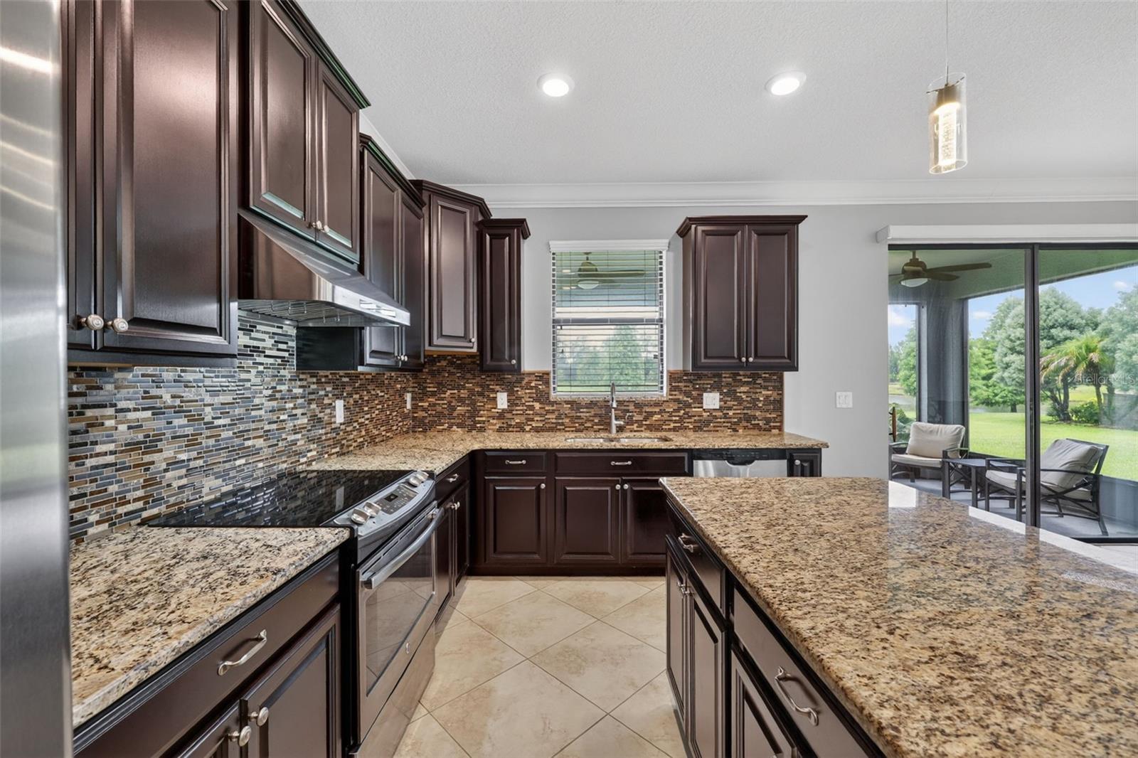 Cooking and Entertaining with a VIEW! Full Gourmet Kitchen with Crown Molding, Island, Pendant & Recessed Lighting, Abundant Cabinets with Crown Trim, Granite Countertops, Backsplash, GE Stainless Steel Appliance Package, Hood, Window overlooking Serene Pond and Access to Butler's Pantry and Pantry Closet.