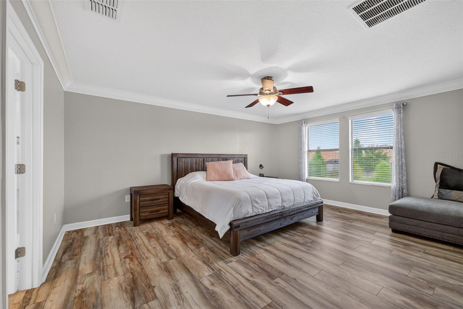 Primary Suite with LVP Floors, Crown Molding, Ceiling Fan, En-Suite Primary Bathroom, Windows Overlooking the View in Waterleaf Community! Enough Room for a King Bed and creating a Sitting Area.