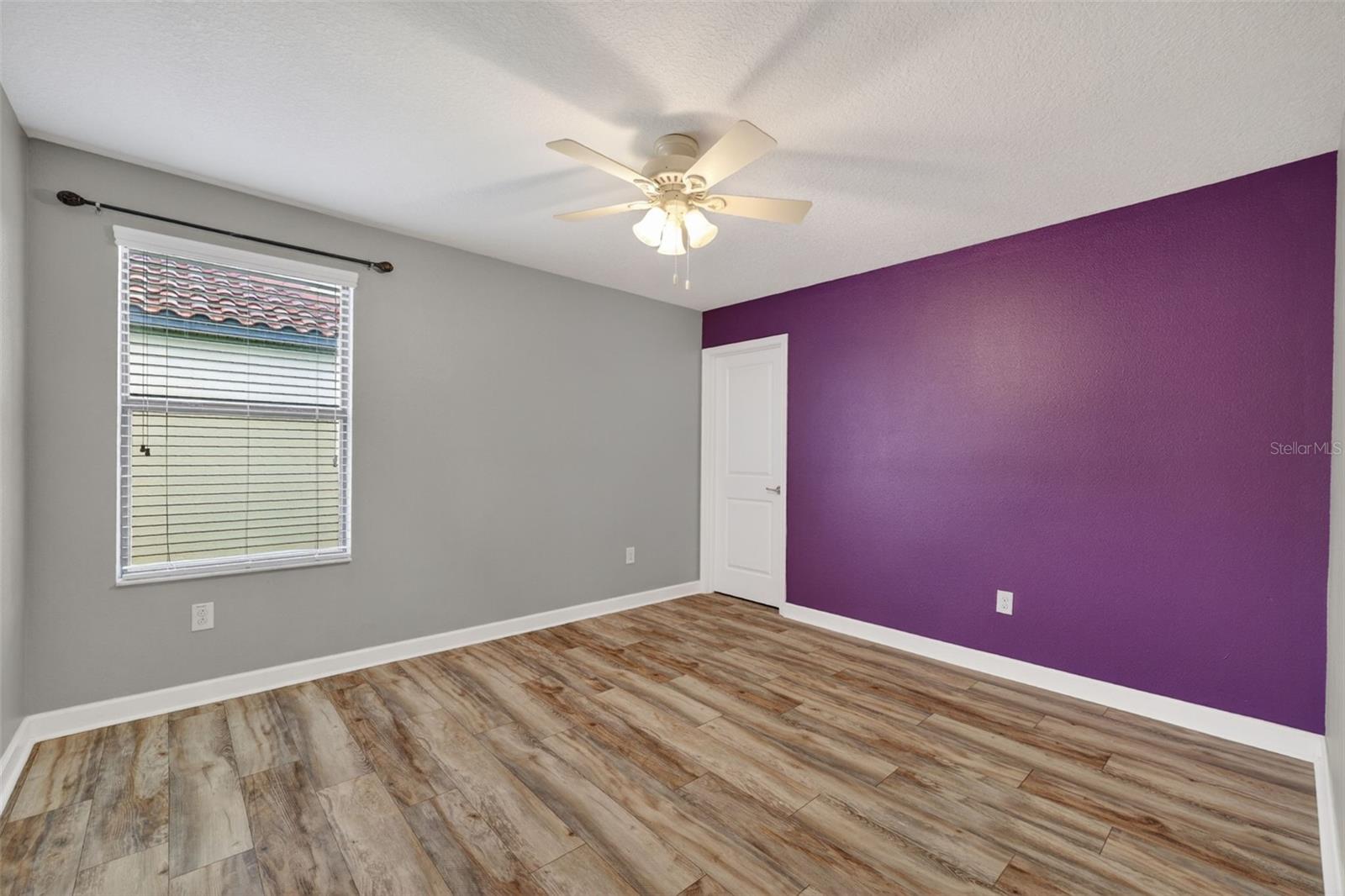 Bedroom #3 with LVP Flooring, Ceiling Fan, Walk-In Closet, Accent Wall and Window.