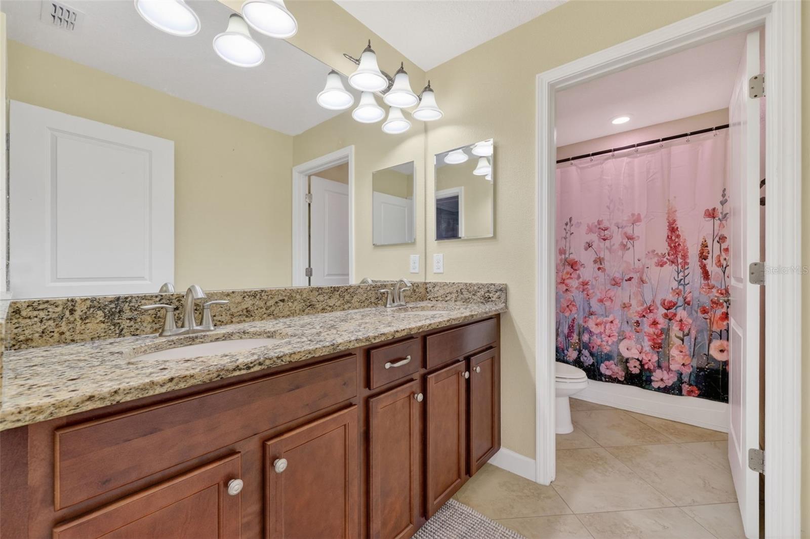 Full Bathroom with Dual Vanities, Granite Countertops, and Shower/Tub Combination.
