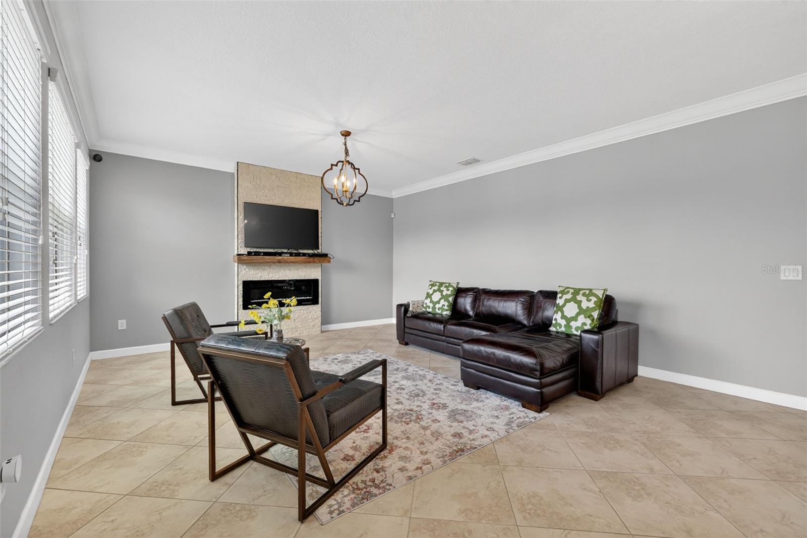 Living Room with Crown Molding, 3 Stunning Windows, Accent Wall with Stone Accent and Chandelier.
