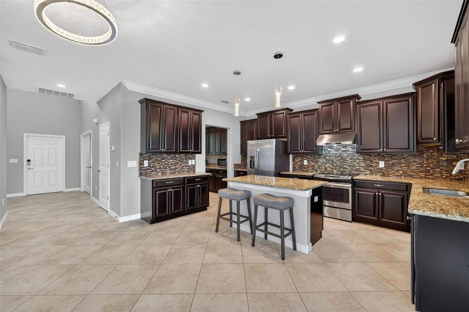 Envision a Coffee or Wine Bar - Space for it All! Full Gourmet Kitchen with Crown Molding, Island, Pendant & Recessed Lighting, Abundant Cabinets with Crown Trim, Granite Countertops, Backsplash, GE Stainless Steel Appliance Package, Hood, Window overlooking Serene Pond and Access to Butler's Pantry and Pantry Closet.