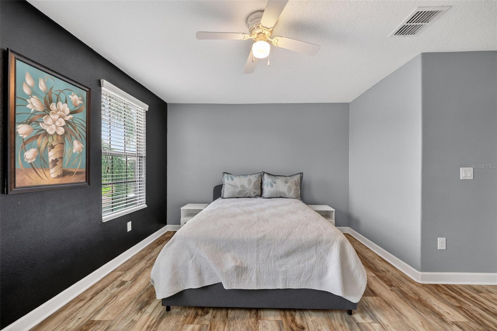 Bedroom #2 with LVP Flooring, Ceiling Fan, Walk-In Closet and Windows Overlooking the Front of the Home.