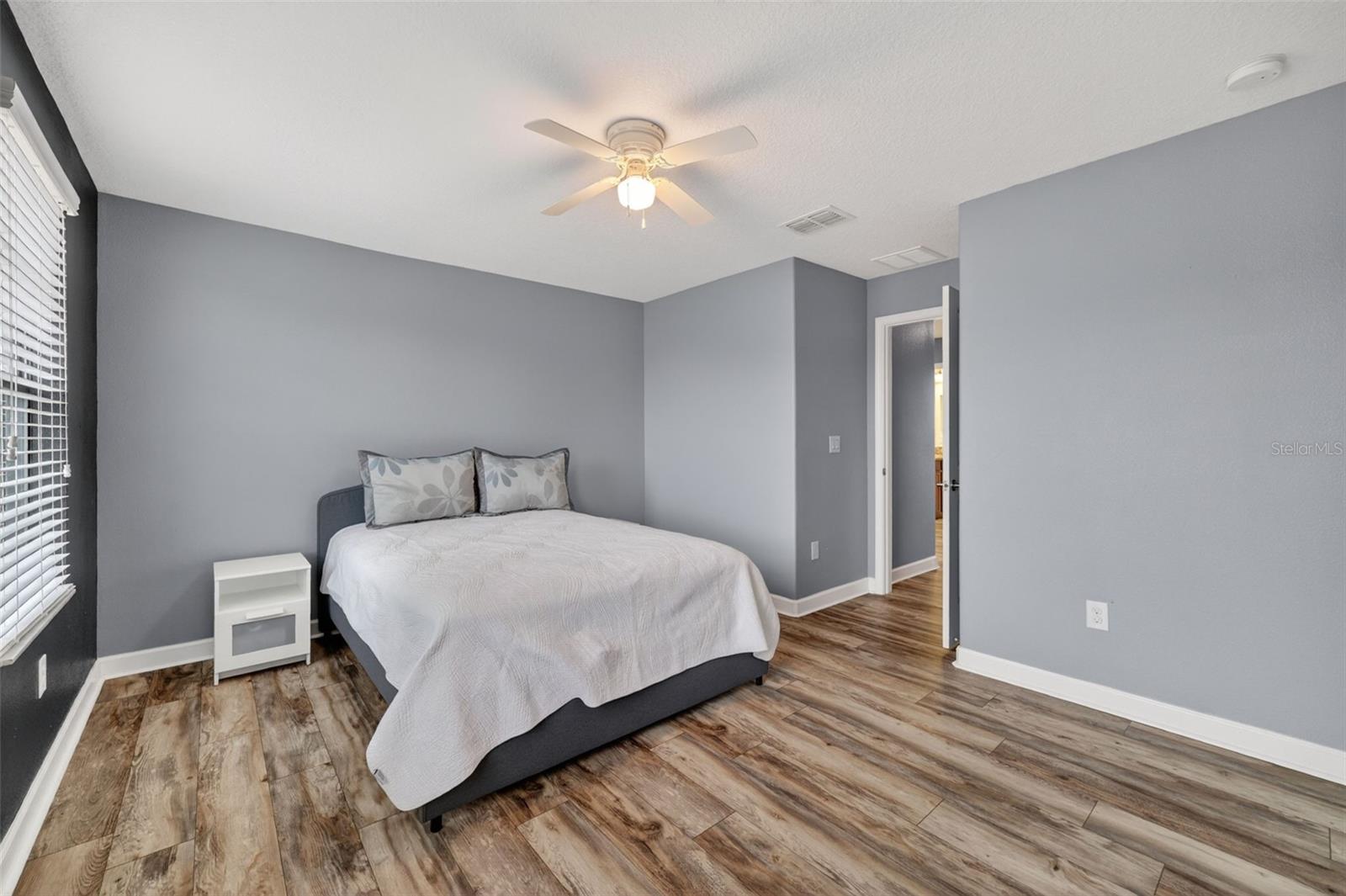 Bedroom #2 with LVP Flooring, Ceiling Fan, Walk-In Closet and Windows Overlooking the Front of the Home.