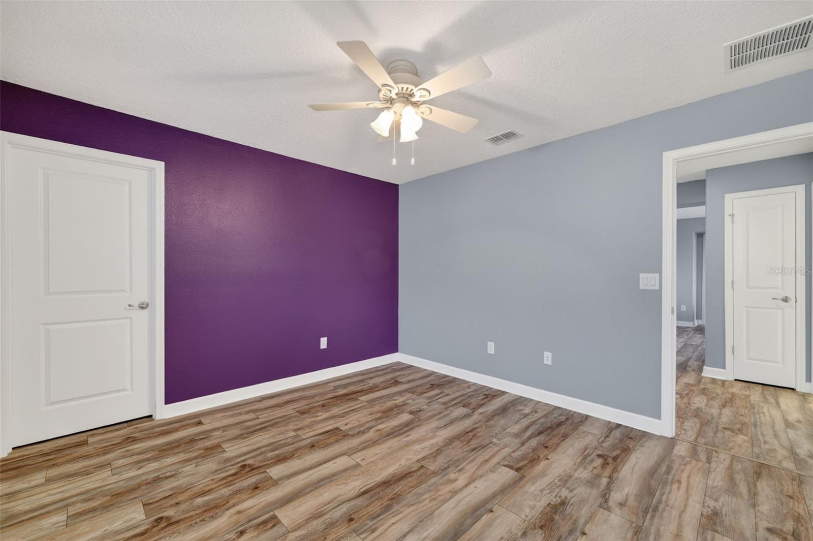 Bedroom #3 with LVP Flooring, Ceiling Fan, Walk-In Closet, Accent Wall and Window.