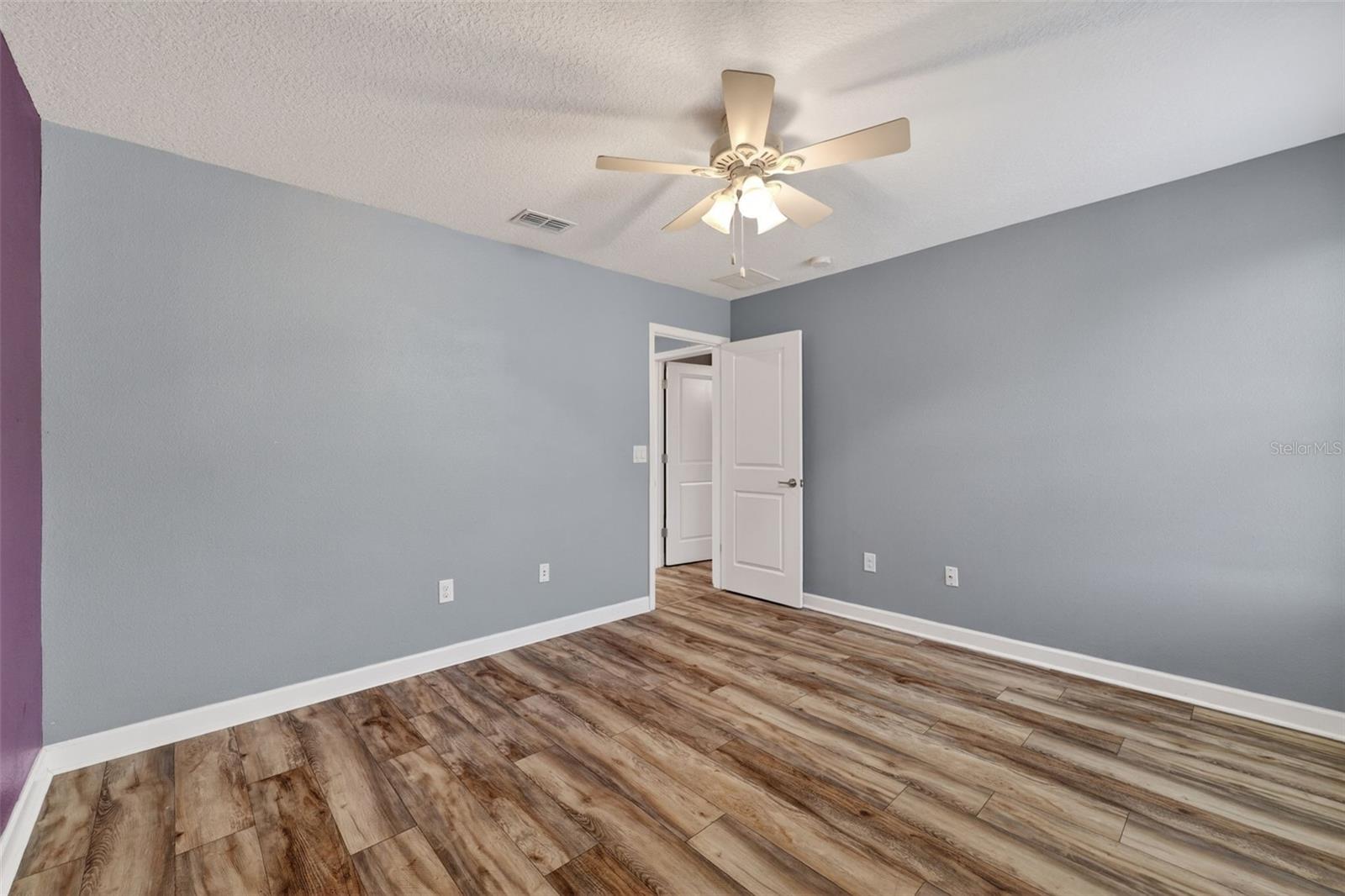 Bedroom #3 with LVP Flooring, Ceiling Fan, Walk-In Closet, Accent Wall and Window.