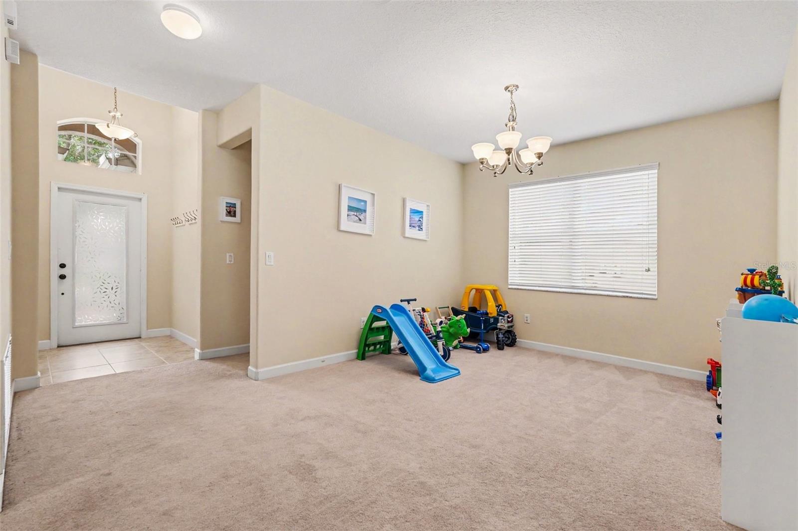 Large flex space with chandelier and open view toward foyer entry. Adaptable as formal living, or hobby/game space in Tampa FL 33647. Junior suite to the far right