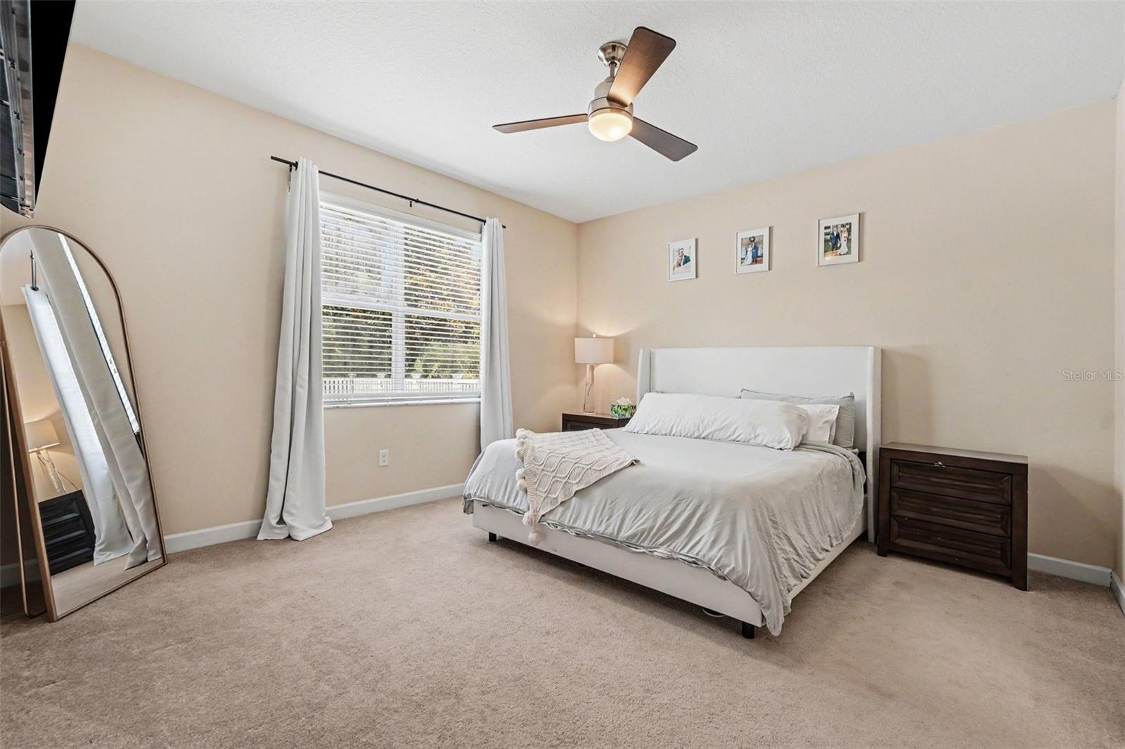 Spacious primary bedroom suite with natural light, ceiling fan, and window with backyard view in Tampa FL 33647. Walk in closet and en suite to the right (not visible)