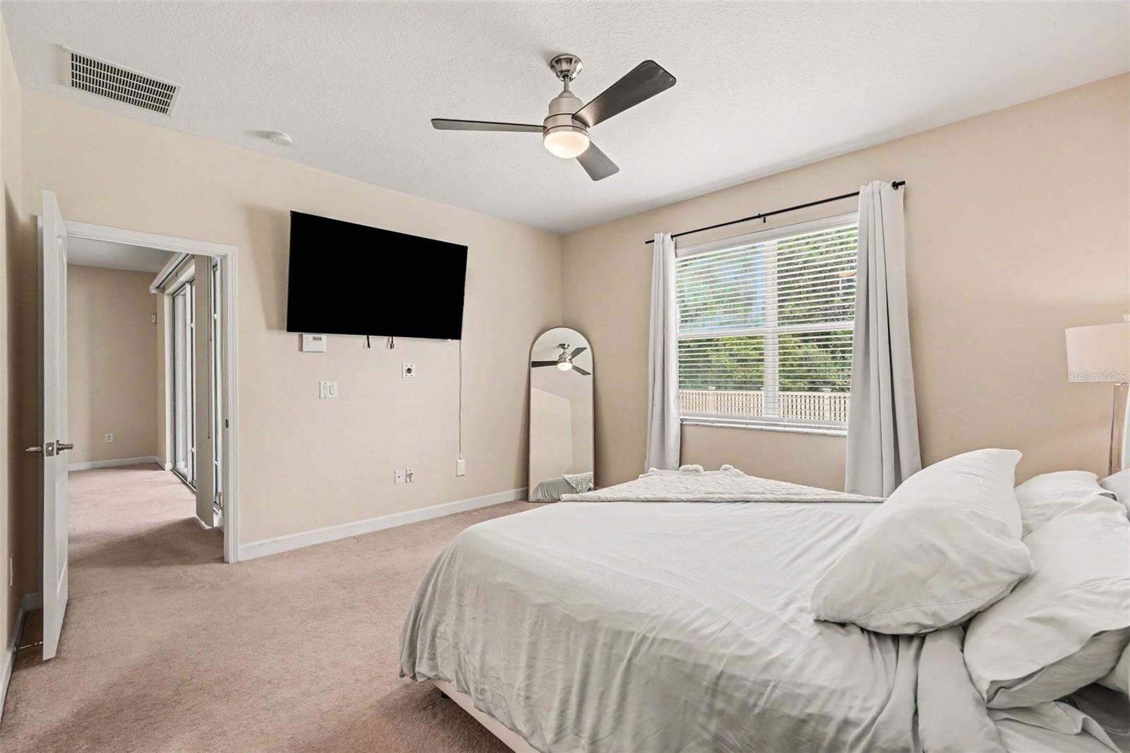 Primary bedroom suite with en-suite bathroom, ceiling fan, and natural light in Tampa FL 33647