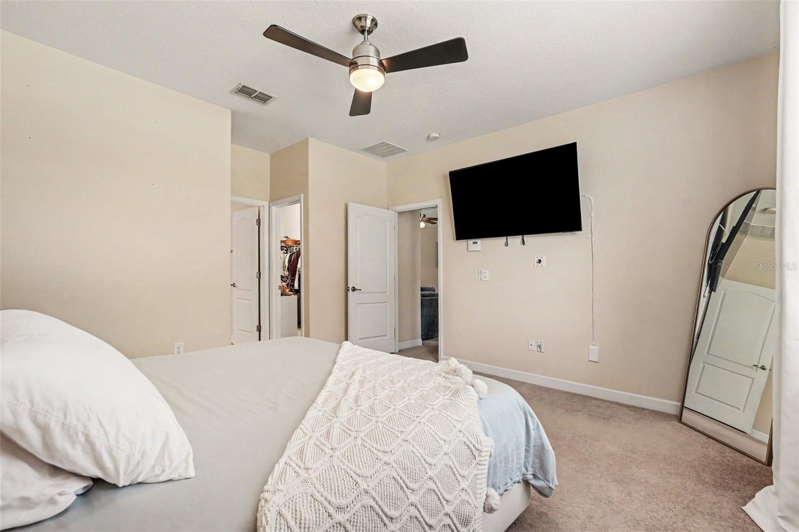 Primary bedroom suite third angle showing walk-in closet open, TV mount, and en-suite access in Tampa FL 33647
