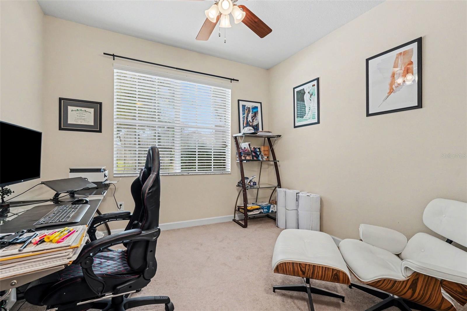 Second bedroom/junior suite via pocket door access, currently used as home office with desk, ceiling fan, natural light in Tampa FL 33647