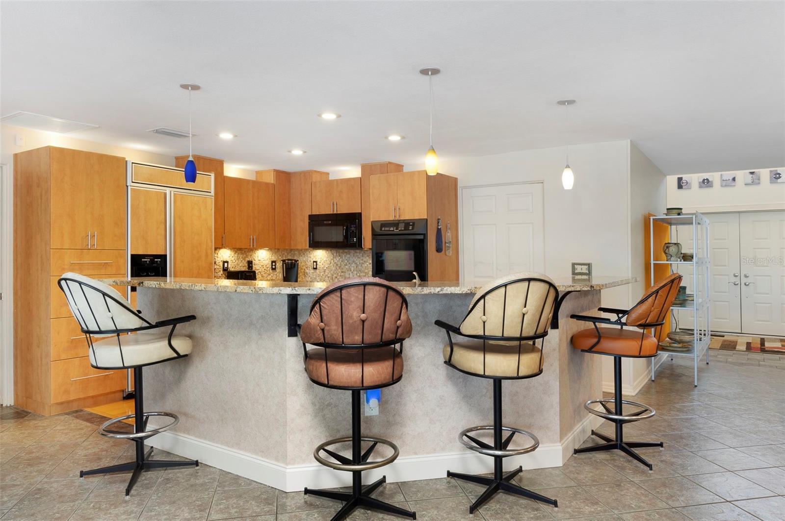 Large island with granite countertop is heart of home and is perfect place to gather with friends and family