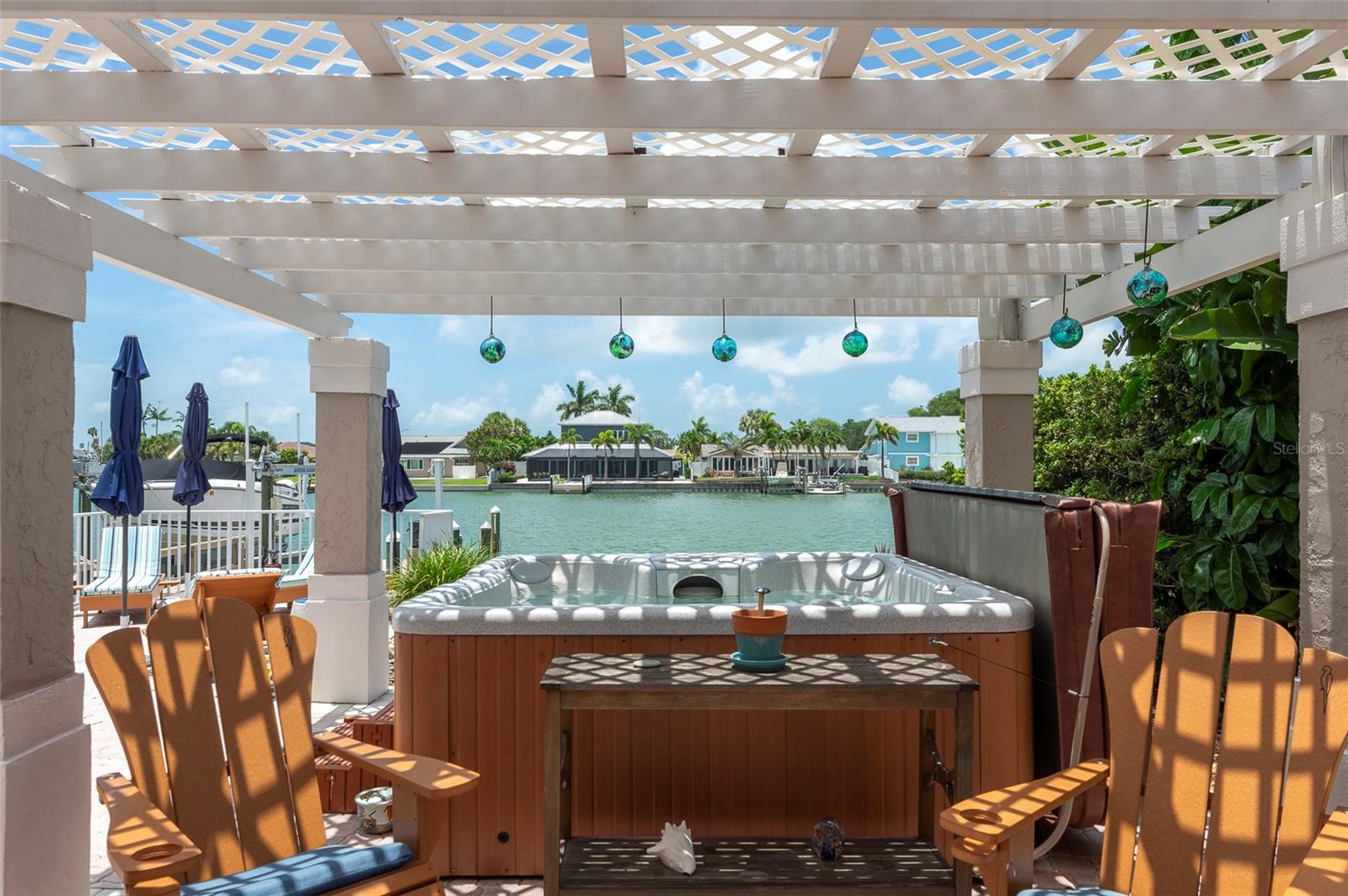 Shady hot tub and seating area overlooks the water