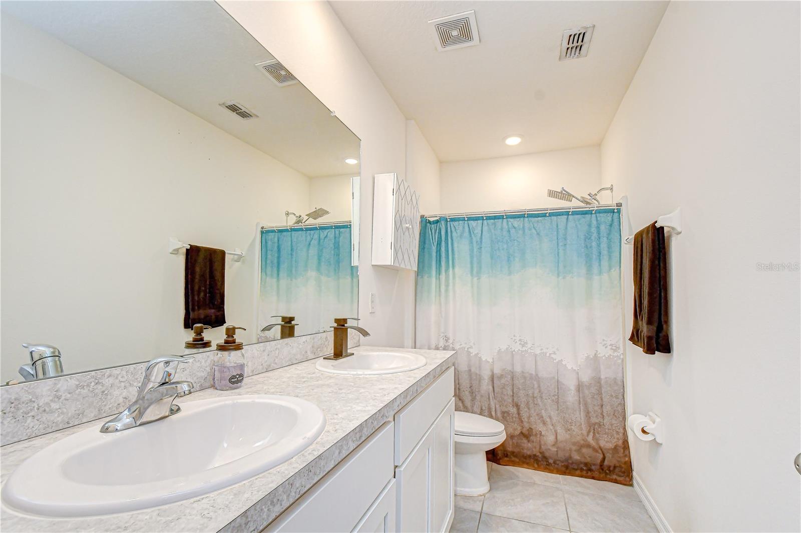 En-suite private bathroom featuring a dual-sink vanity and a spacious glass-enclosed shower.