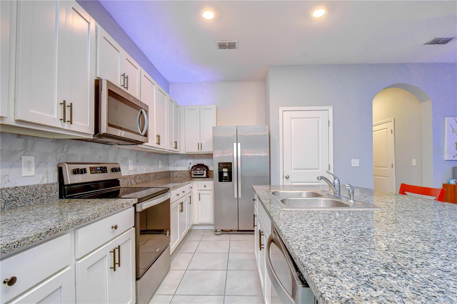 Modern kitchen highlighting sleek stone countertops, stainless steel appliances, and a large center island.