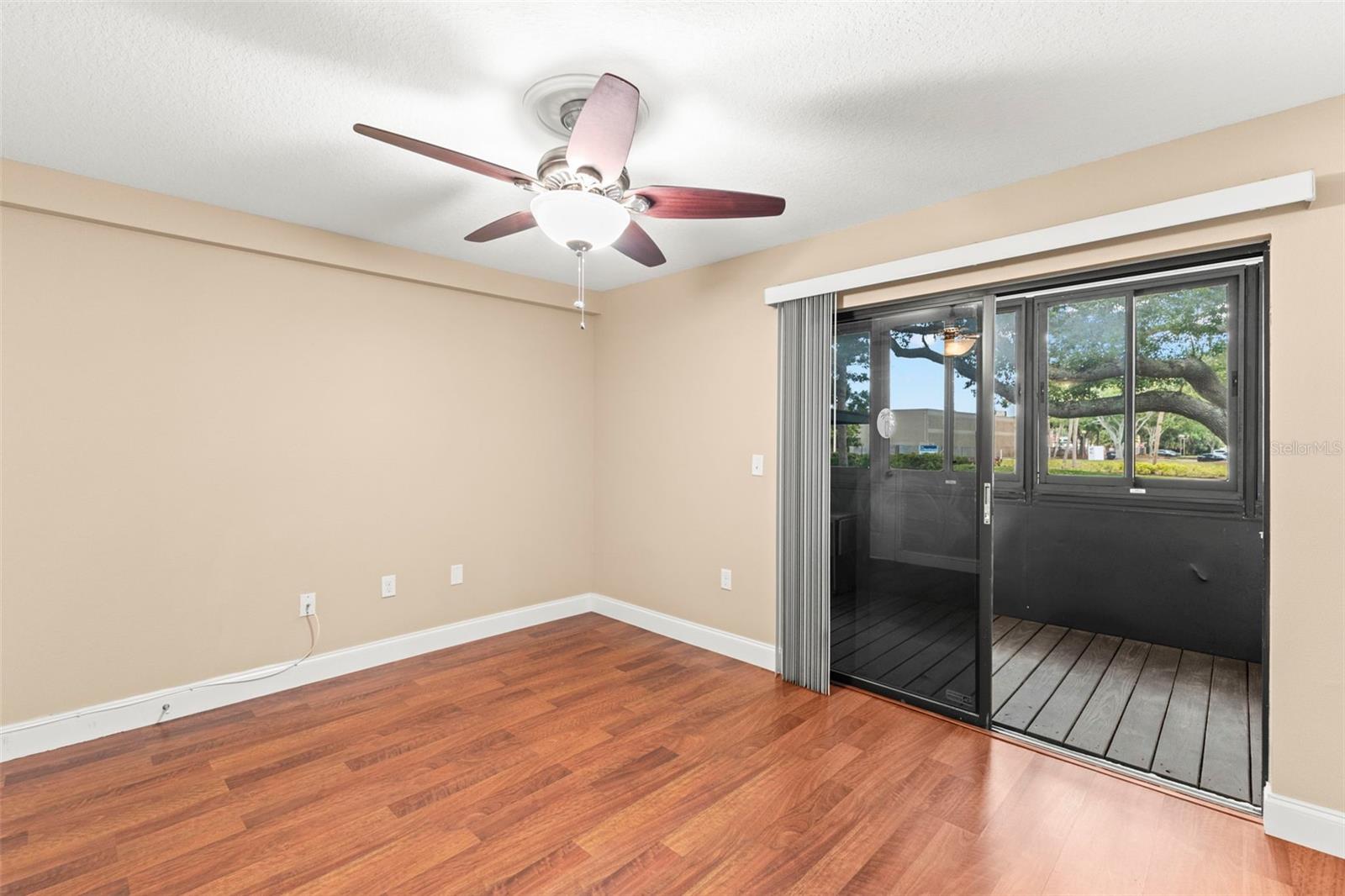 Versatile second bedroom with wood-look flooring, walk-in closet, and direct access to the screened lanai—ideal for guests, a home office, or hobbies.