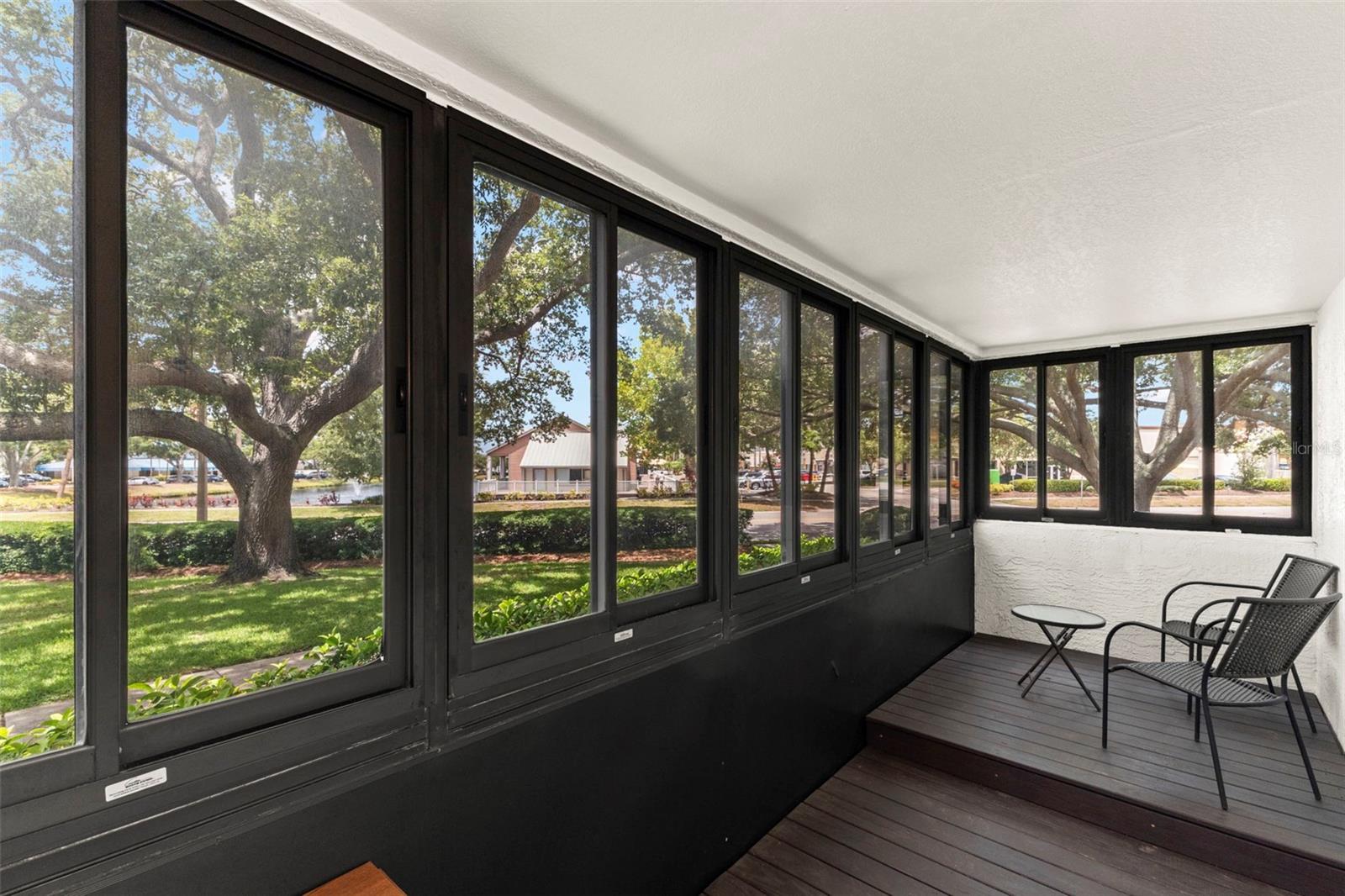 Spacious screened lanai featuring wall-to-wall windows and tranquil views of the beautifully maintained grounds.