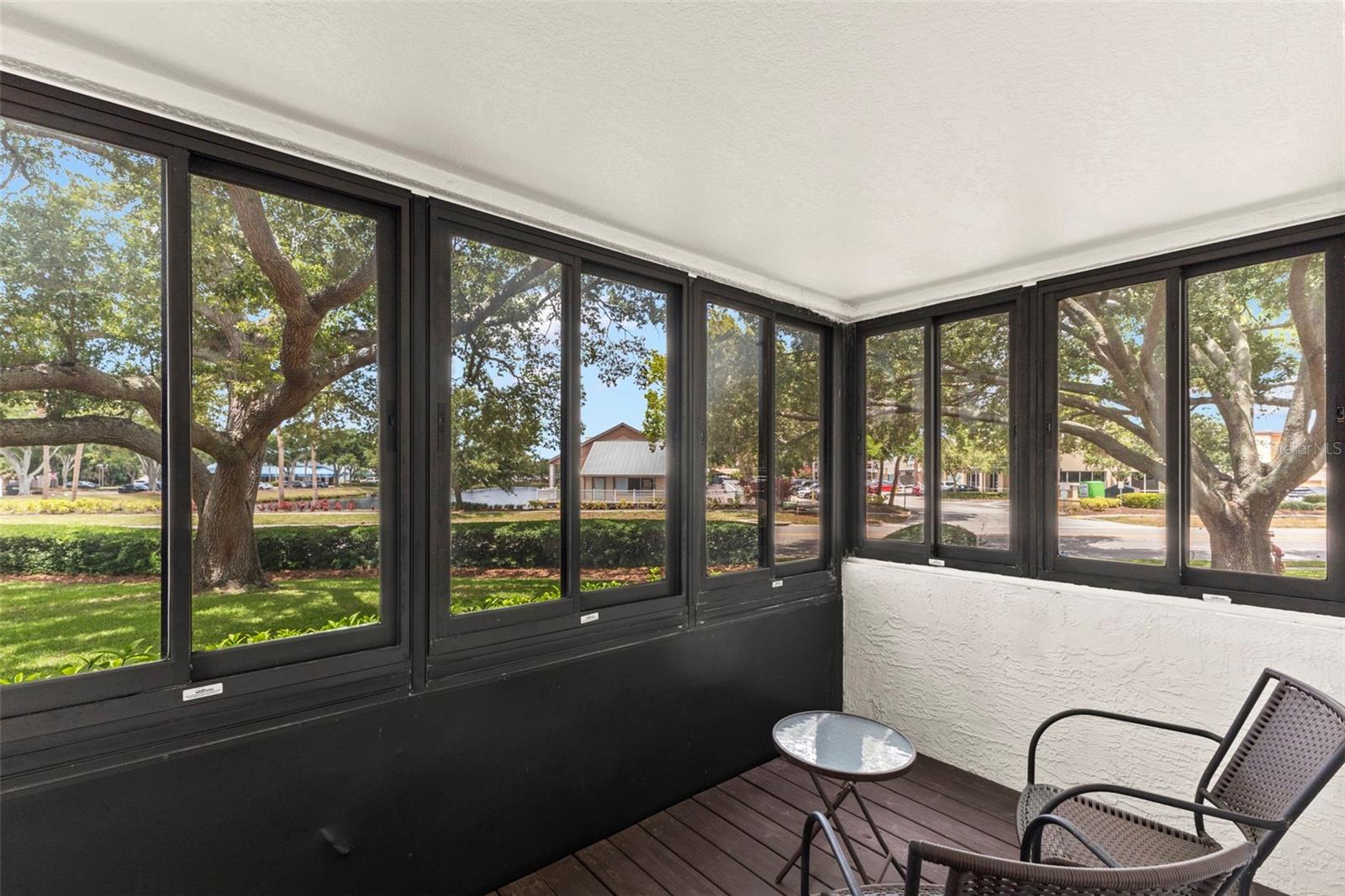 Wall-to-wall windows frame peaceful views of mature oak trees, manicured grounds, and the community pond.