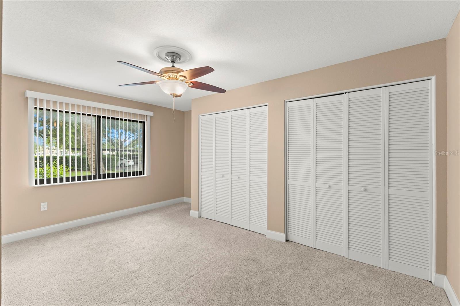 Third bedroom featuring neutral carpeting, a ceiling fan, and dual closets for exceptional storage.