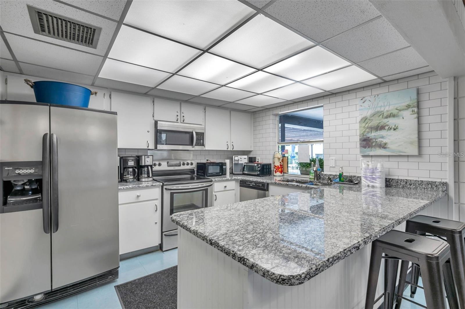 Clubhouse kitchen with stainless steel appliances, generous prep space, and serving area for community events and gatherings.