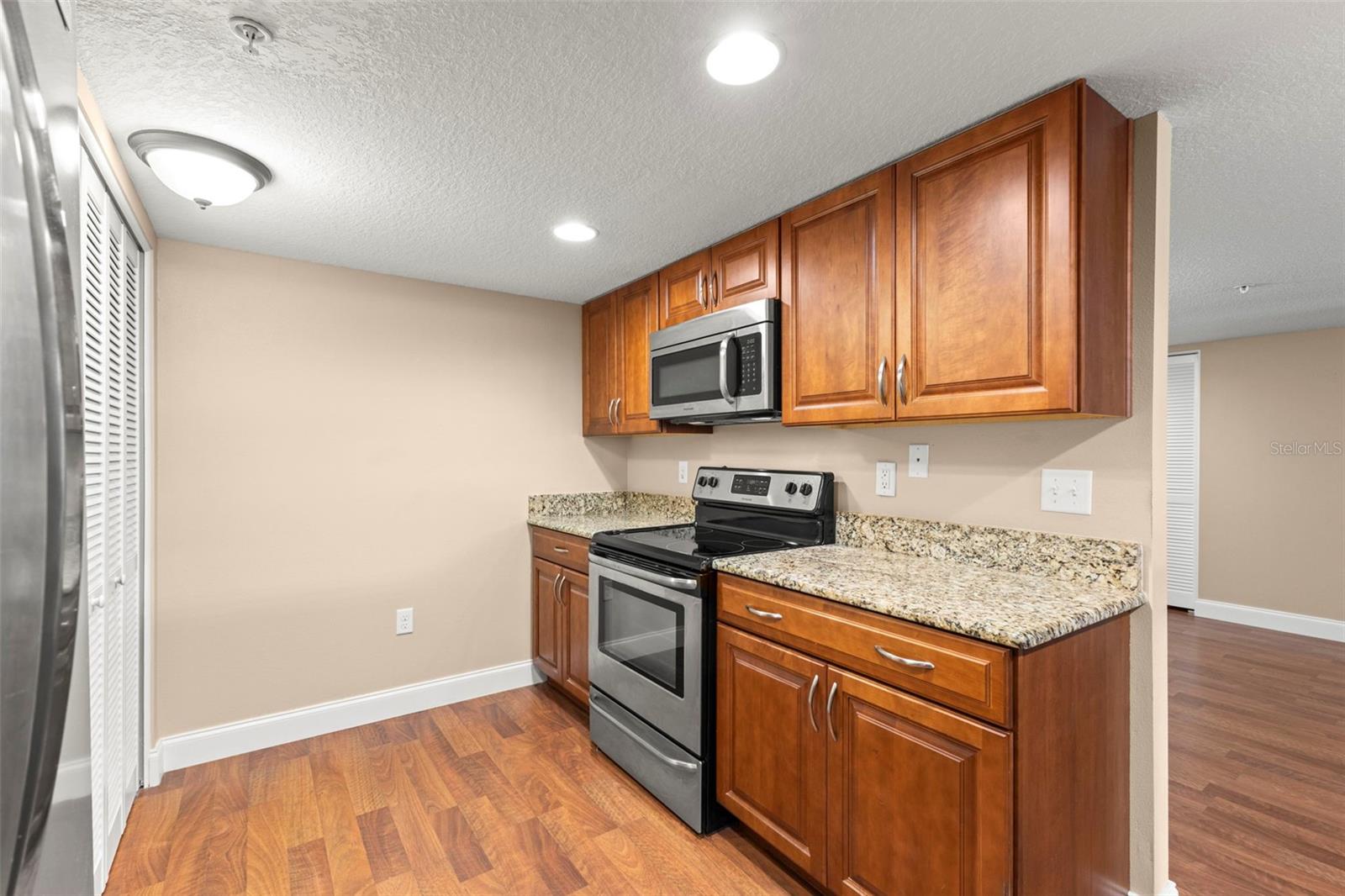 Granite countertops, extensive wood cabinetry, a built-in microwave, electric range, and generous counter space create a kitchen designed for efficiency and convenience.