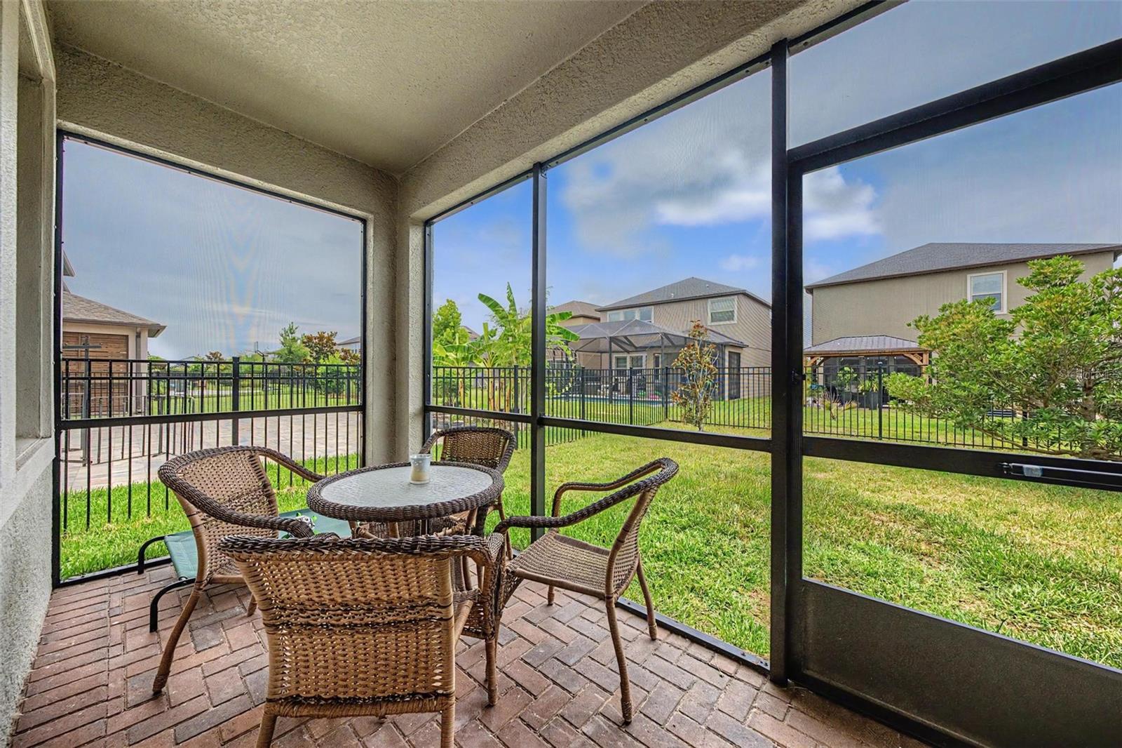 Screened in and pavered patio/lanai with exterior access leads to the fenced-in yard