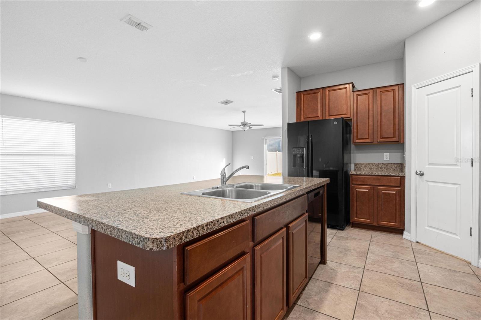 Kitchen with granite countertops, espresso cabinetry, a smooth-top electric range, built-in microwave, dishwasher, French door refrigerator with ice maker and water dispenser, plus a pantry for additional storage.