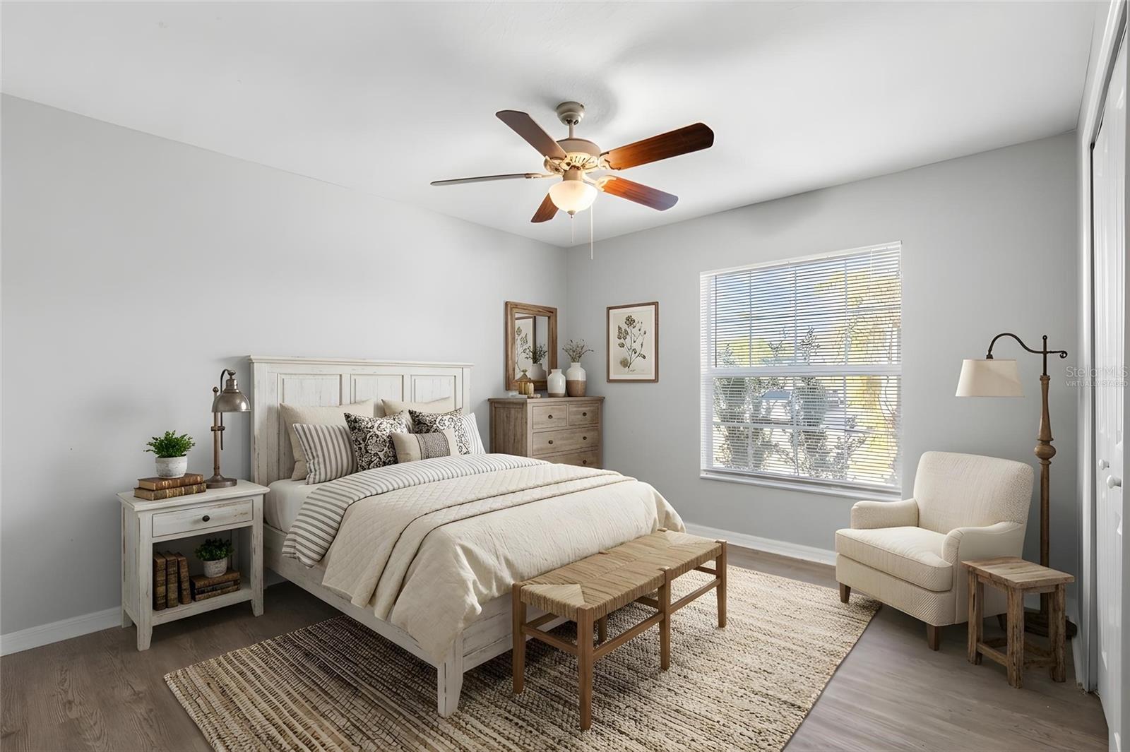 Bedroom 2 features laminate flooring, a ceiling fan, neutral tones, natural light, and a built-in closet.