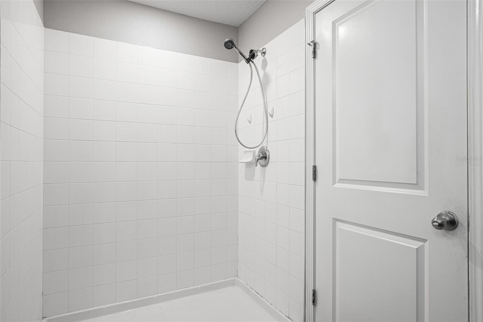 Virtually staged spacious primary walk-in closet with wraparound shelving for clothing, shoes, accessories, and organized storage.