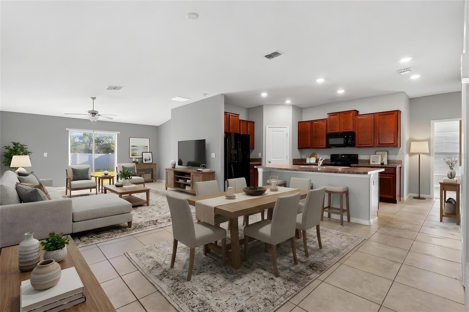 Kitchen featuring a peninsula with breakfast bar seating and sink, granite countertops, black appliances, and a walk-in pantry for additional storage.